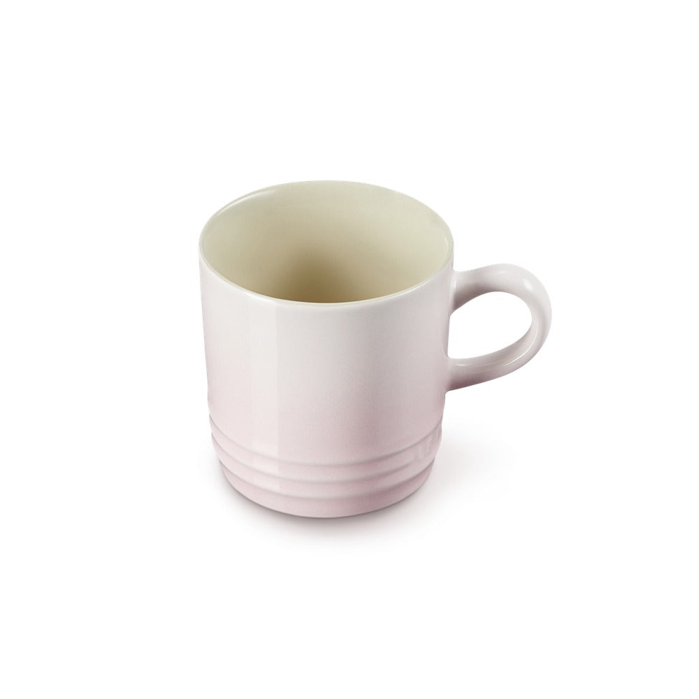 Tazza cilindrica in ceramica, di colore rosa chiaro con interno bianco, presenta linee orizzontali sotto il bordo e un manico.