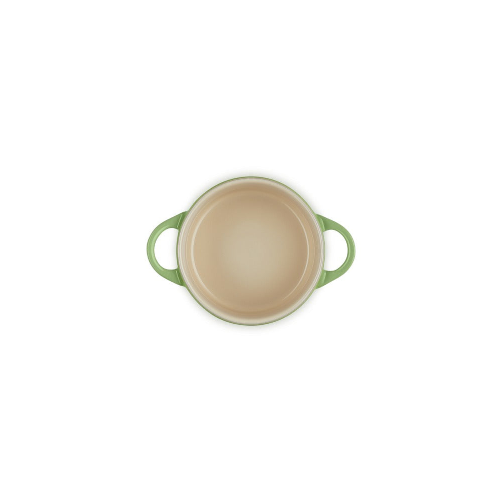 Casseruola rotonda con manici verdi, interna beige, su sfondo bianco.