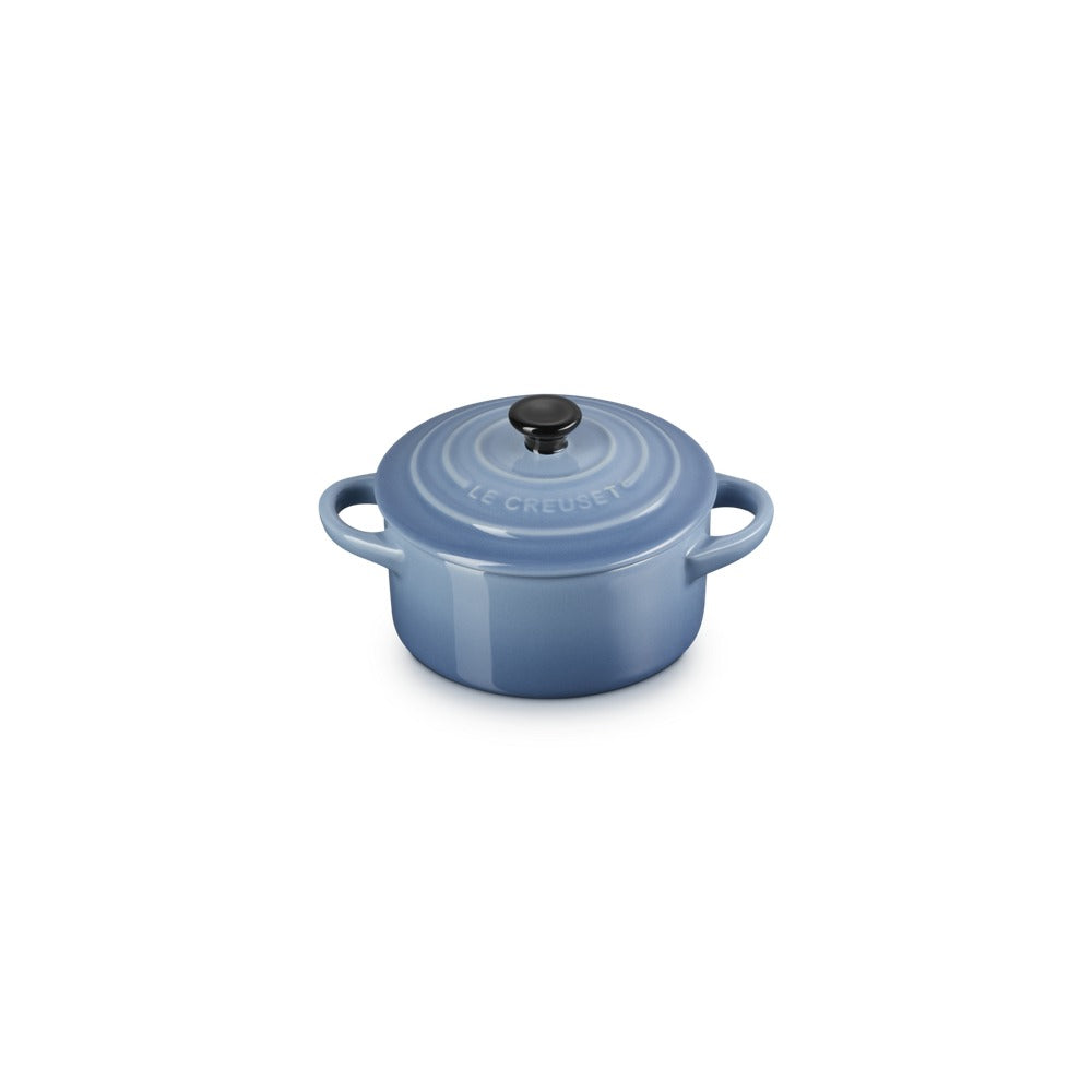 Casseruola rotonda in ceramica blu con manici, coperchio nero e dettagli lucidi, posizionata su sfondo bianco.