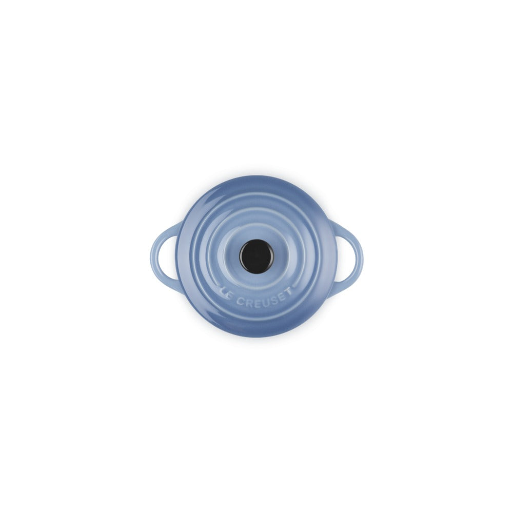 Casseruola tonda in ceramica blu con manici e coperchio nero al centro, su sfondo bianco.