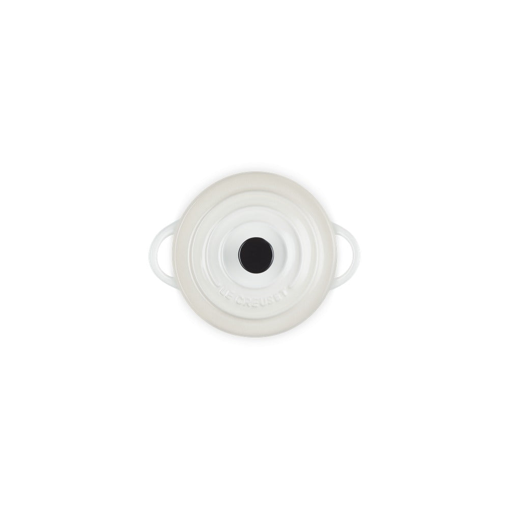 Pentola bianca con rilievi, dotata di manici, con coperchio centrale nero. Logo "LE CREUSET" visibile.