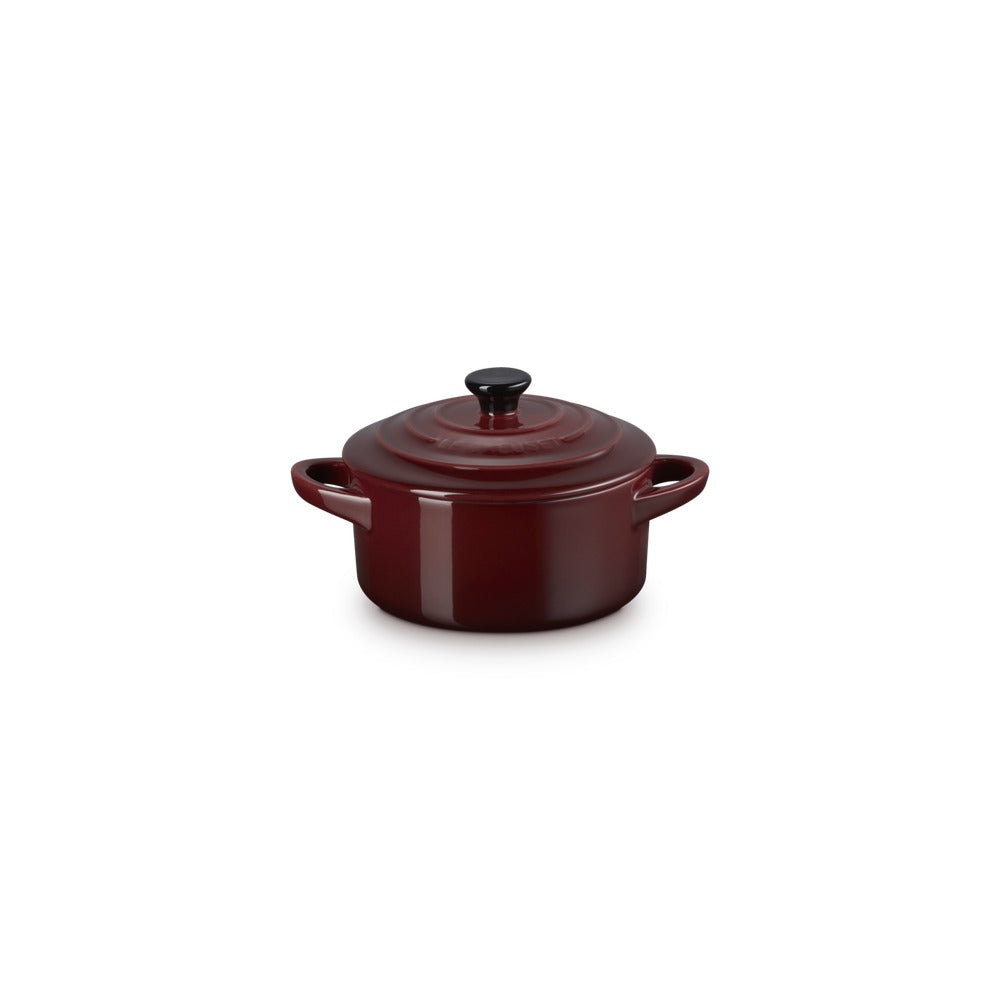 Casseruola rotonda in ceramica rossa con coperchio nero, manici laterali, su sfondo bianco.