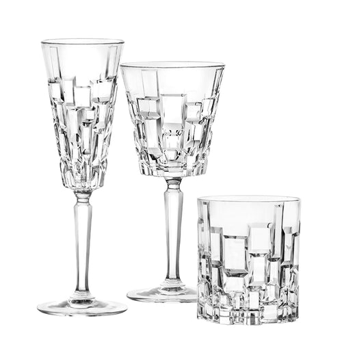 Drei transparente Kristallgläser mit erhabenen geometrischen Verzierungen, ein Weinglas, ein Flute und ein Tumbler, weißer Hintergrund.