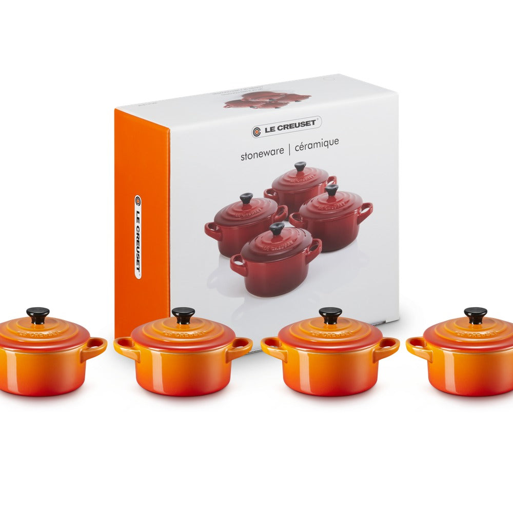 Set de casseroles en céramique rouge et orange, avec couvercles noirs, à côté de l'emballage de la marque Le Creuset.