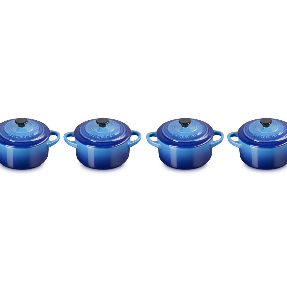 Set di quattro cocotte in ceramica blu, con coperchio e manico, presenti su uno sfondo bianco.