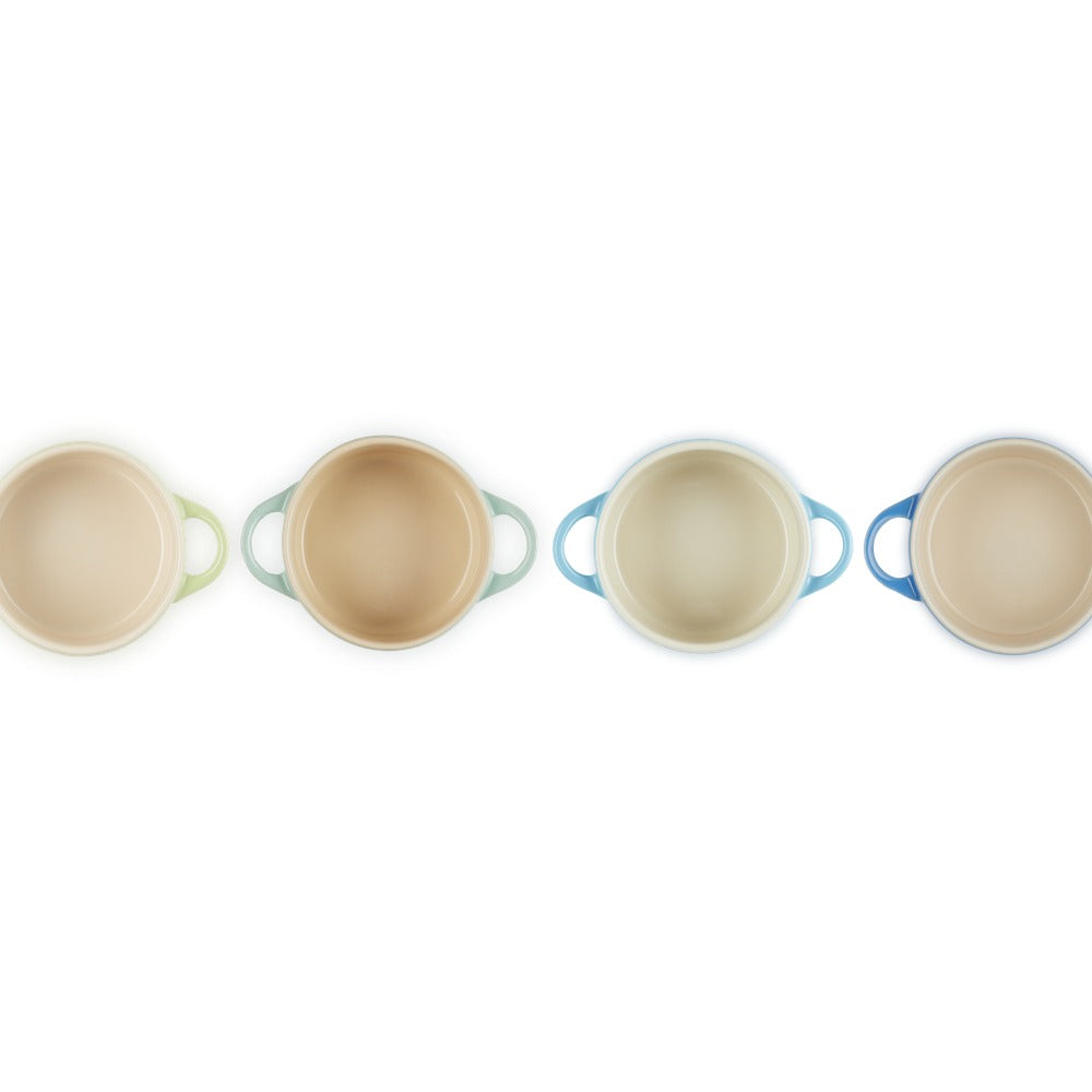 Quatre casseroles en céramique aux couleurs pastel (vert, beige, bleu), avec poignées et forme circulaire, sur fond blanc.