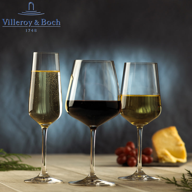 Tre calici di vetro: uno con bollicine dorate, uno con vino rosso e uno con bevanda giallo dorato. Sfondo sfumato blu.