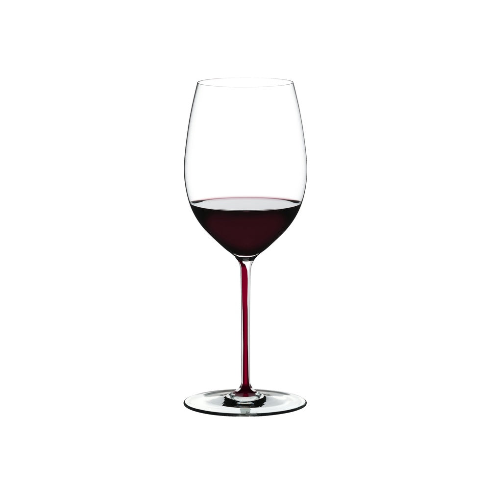 Calice di vino trasparente con stelo sottile, contenente vino rosso scuro, su sfondo bianco.