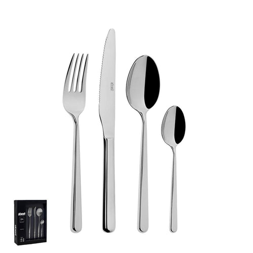 Set di posate in acciaio inox lucido: forchetta, coltello, cucchiaio grande e piccolo, confezione nera visibile sullo sfondo.