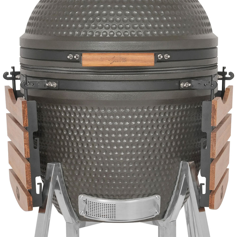 Grauer keramischer eiförmiger Grill mit Metallstruktur und seitlichen Holzgriffen, isoliert auf weißem Hintergrund.