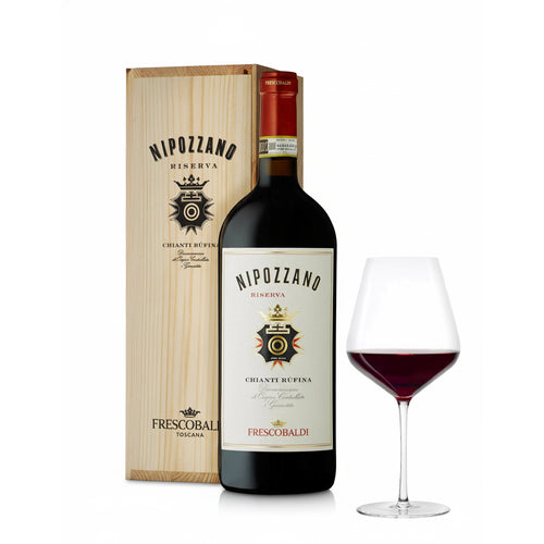 Bottiglia di vino rosso Nipozzano Riserva con etichetta bianca e logo dorato, scatola in legno chiaro e calice con vino rosso.