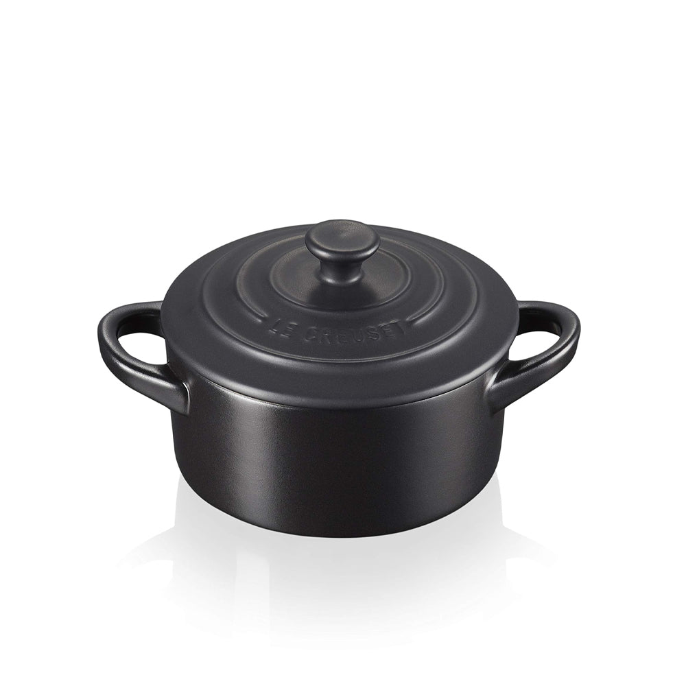 Pentola cocotte in ghisa nera opaca con due manici e coperchio con pomolo centrale, logo Le Creuset inciso sul coperchio.
