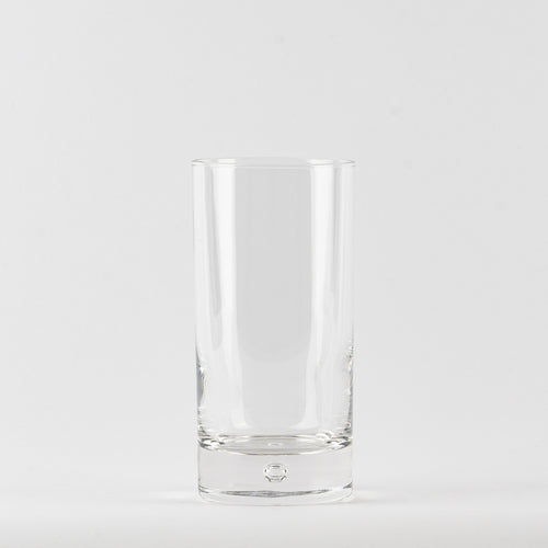 Transparentes zylindrisches Glas mit dicker Basis auf einheitlichem weißem Hintergrund.