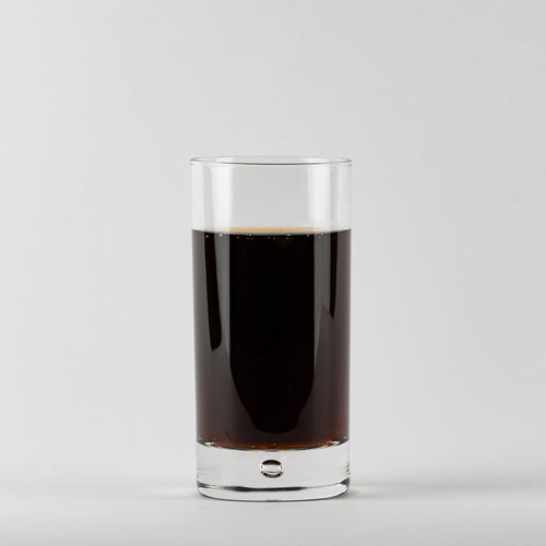 Cylindrical Glasbecher aus Glas transparent mit dense dark drink auf uniform weißer Hintergrund.