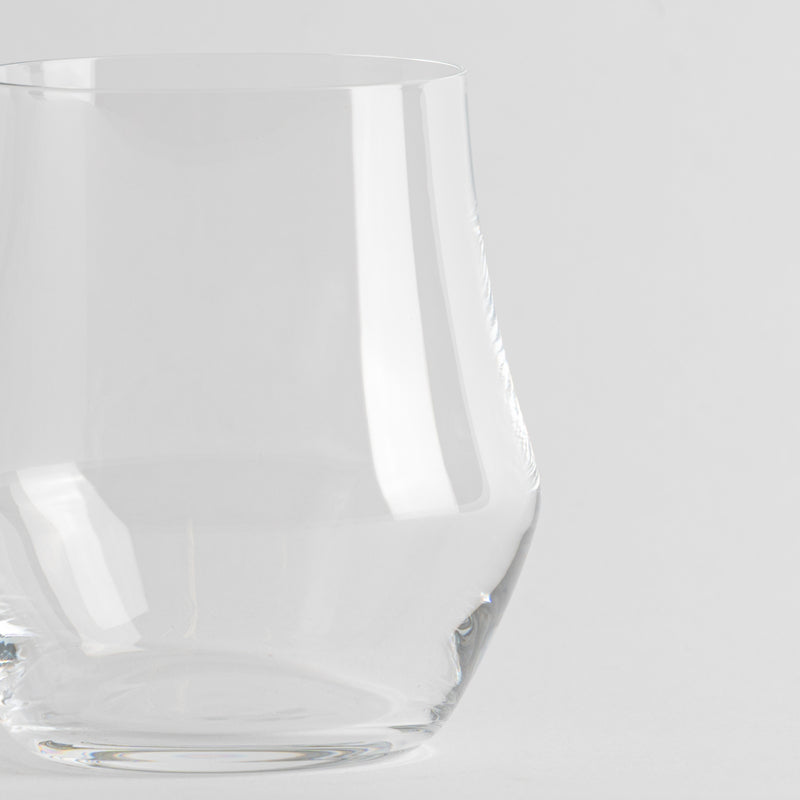 Verre transparent en verre avec base épaisse et parois légèrement courbes sur fond blanc uniforme