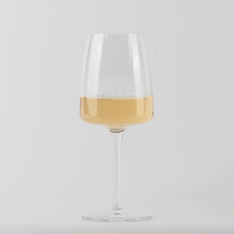 transparent stemmed glass in glass with white wine chiaro on neutral white background
