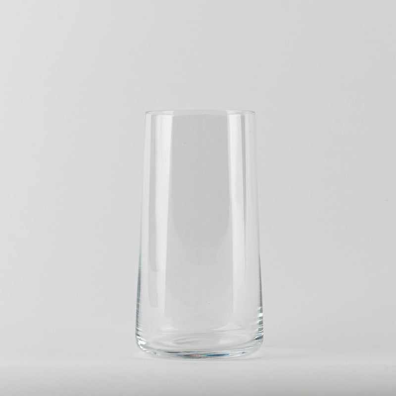 Vaso transparente de cristal con forma cilíndrica ligeramente cónica sobre fondo blanco uniforme.