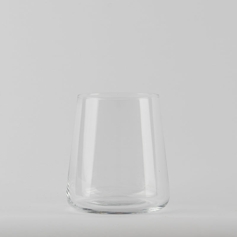 Verre transparent en verre avec base ronde et parois légèrement coniques sur fond gris clair