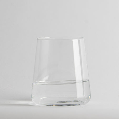 Transparenter Glasbecher mit acqua half full auf neutral light background