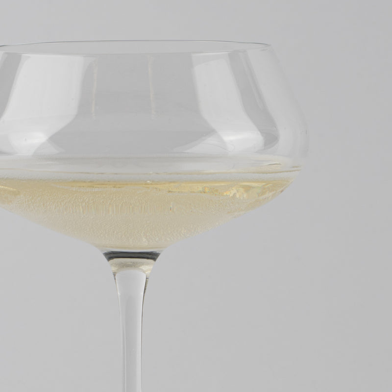 Verre à vin en verre transparent avec liquide pétillant de couleur claire sur fond gris uniforme