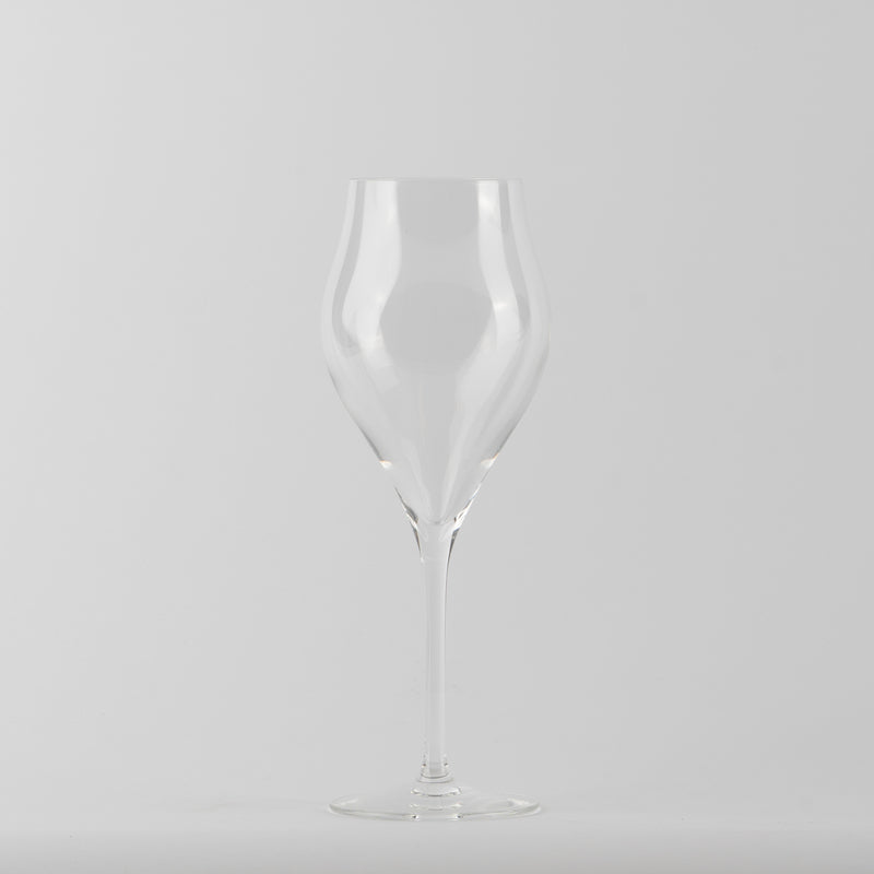 Verre à vin en verre transparent à tige fine et base ronde sur fond gris clair uniforme.