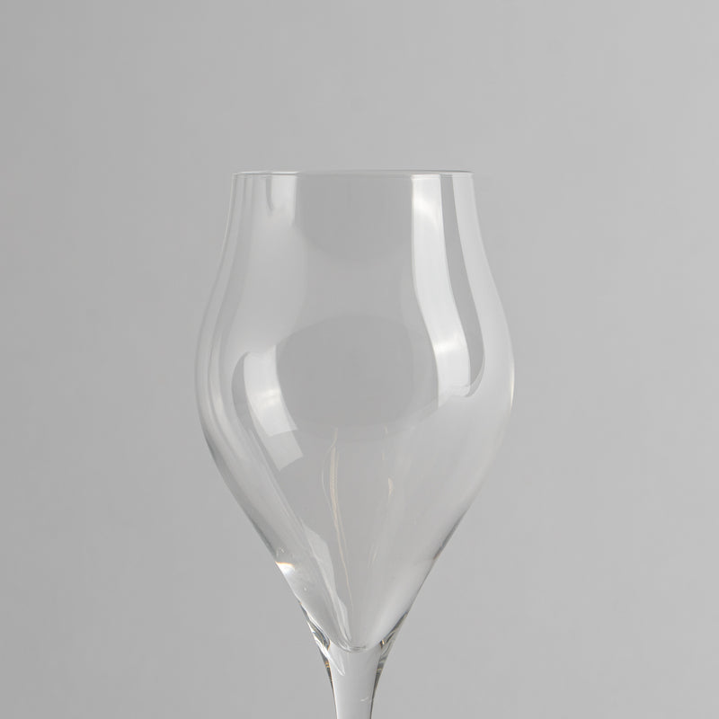 Verre transparent en verre de forme irrégulière avec large coupe et tige fine sur fond gris clair