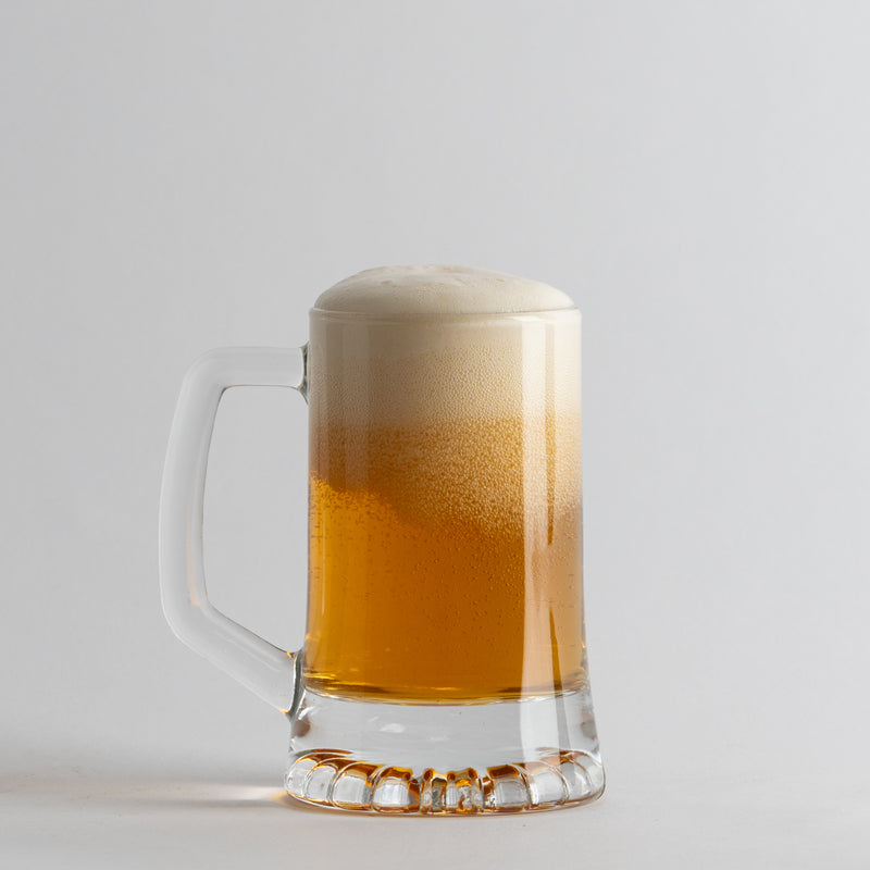 Transparante glazen bierpul met gouden bier en wit schuim op lichtgrijze achtergrond
