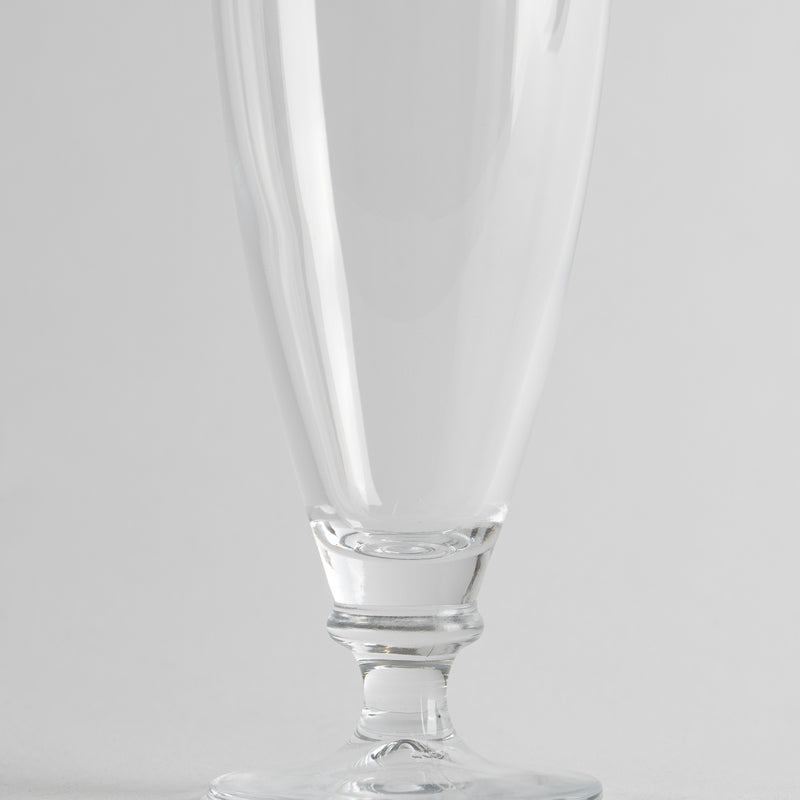 Calice en verre transparent avec pied court et base ronde sur fond gris clair