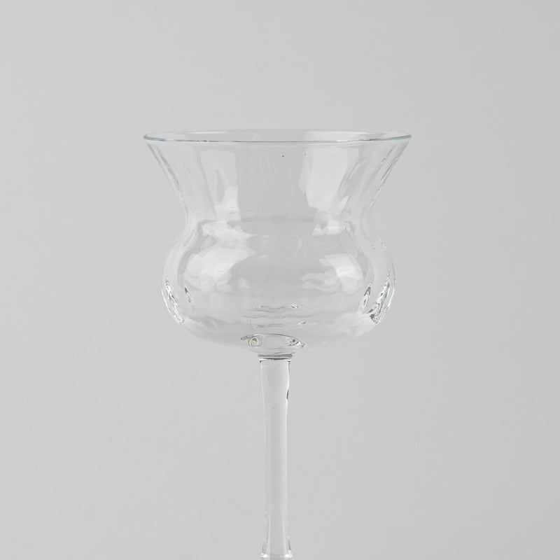 Transparant geblazen glas met brede uitlopende kelk op dunne steel, lichtgrijze achtergrond