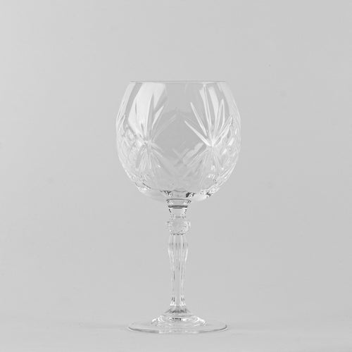 Transparentes Kristallglas mit geometrischen Gravuren auf weißem Hintergrund.