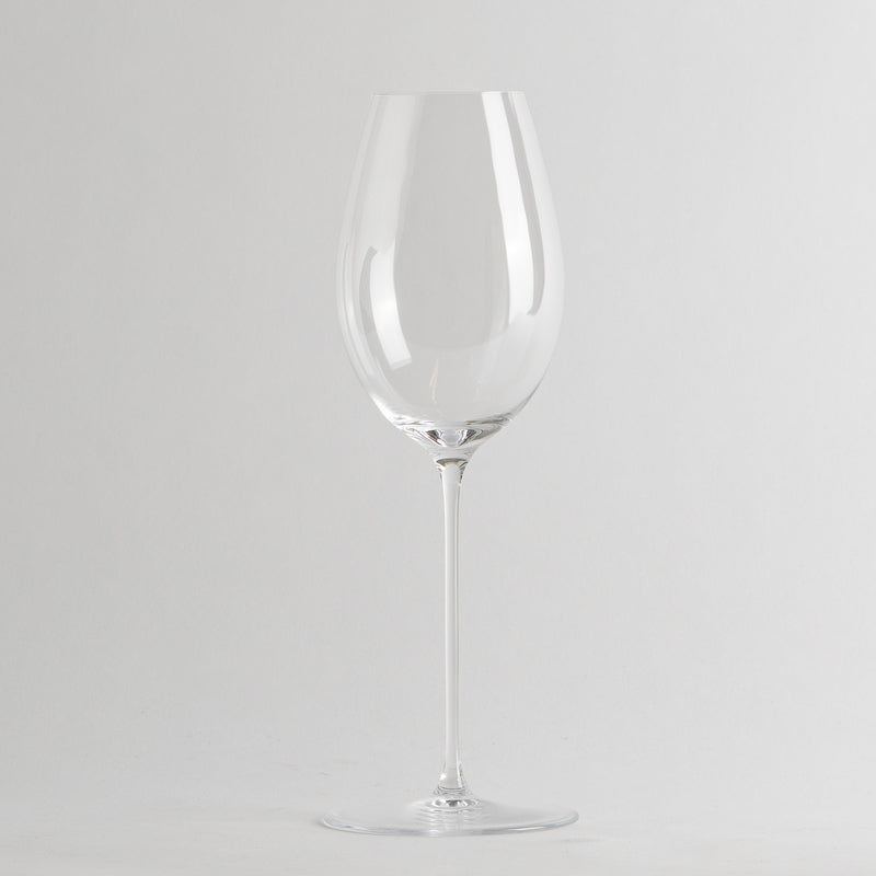 bicchiere da vino trasparente in vetro con gambo sottile e base tonda su sfondo grigio chiaro