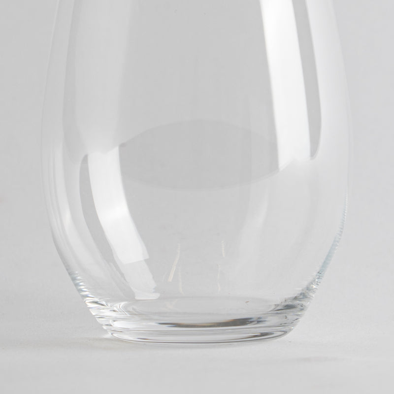 Transparant glas met afgeronde vorm op wit oppervlak, lichte achtergrond.