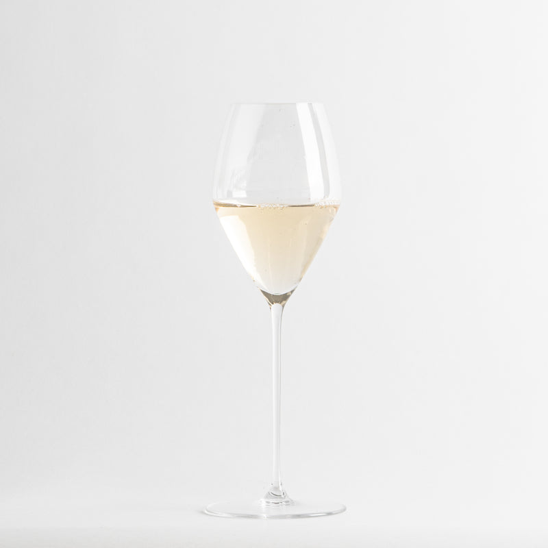Copa de vino blanco transparente con líquido amarillo pálido sobre fondo blanco