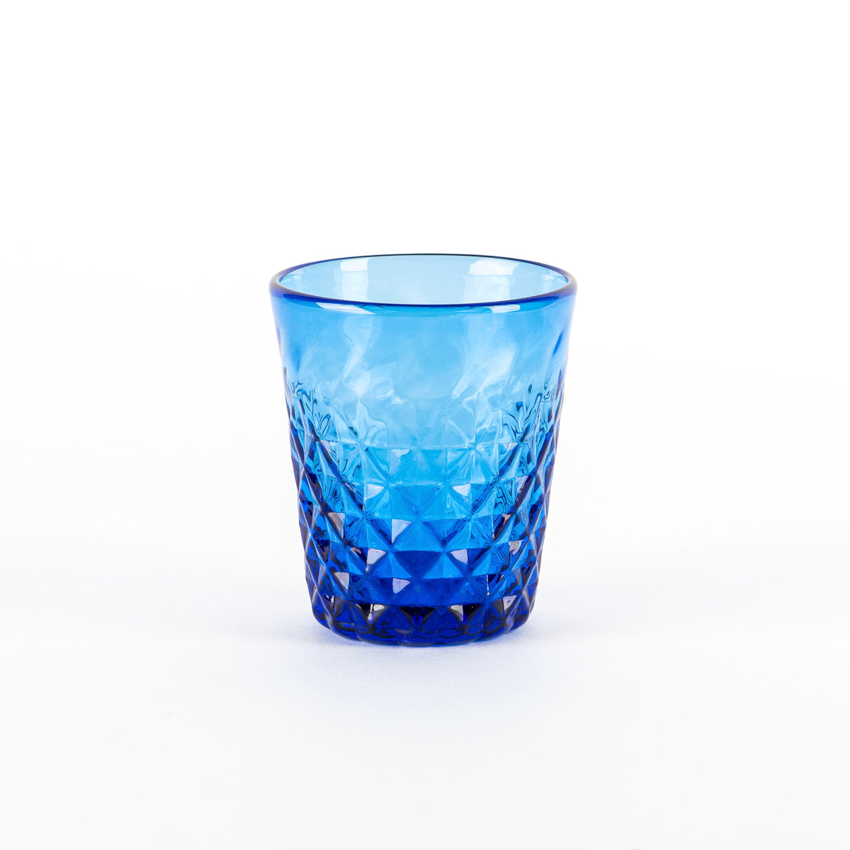 Verre turquoise en verre avec surface facettée et motifs en losange, sur fond blanc neutre.