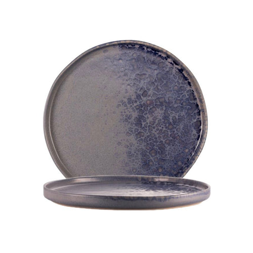 Due piatti tondi in ceramica smerigliata, colorazione grigio lavanda con smalto a effetto puntinato, sfondo bianco.