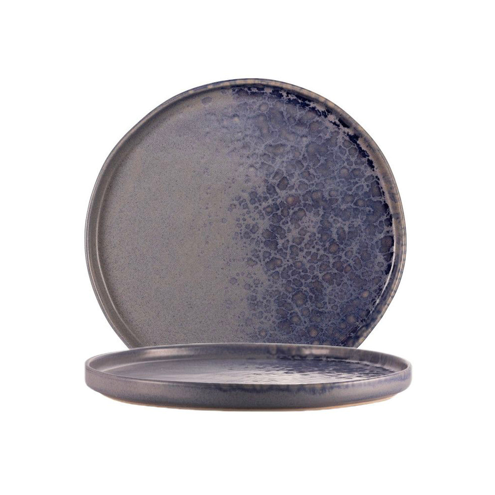 deux assiettes rondes en céramique émaillée bleue avec motif dégradé et texture irrégulière, l'une debout et l'autre couchée.