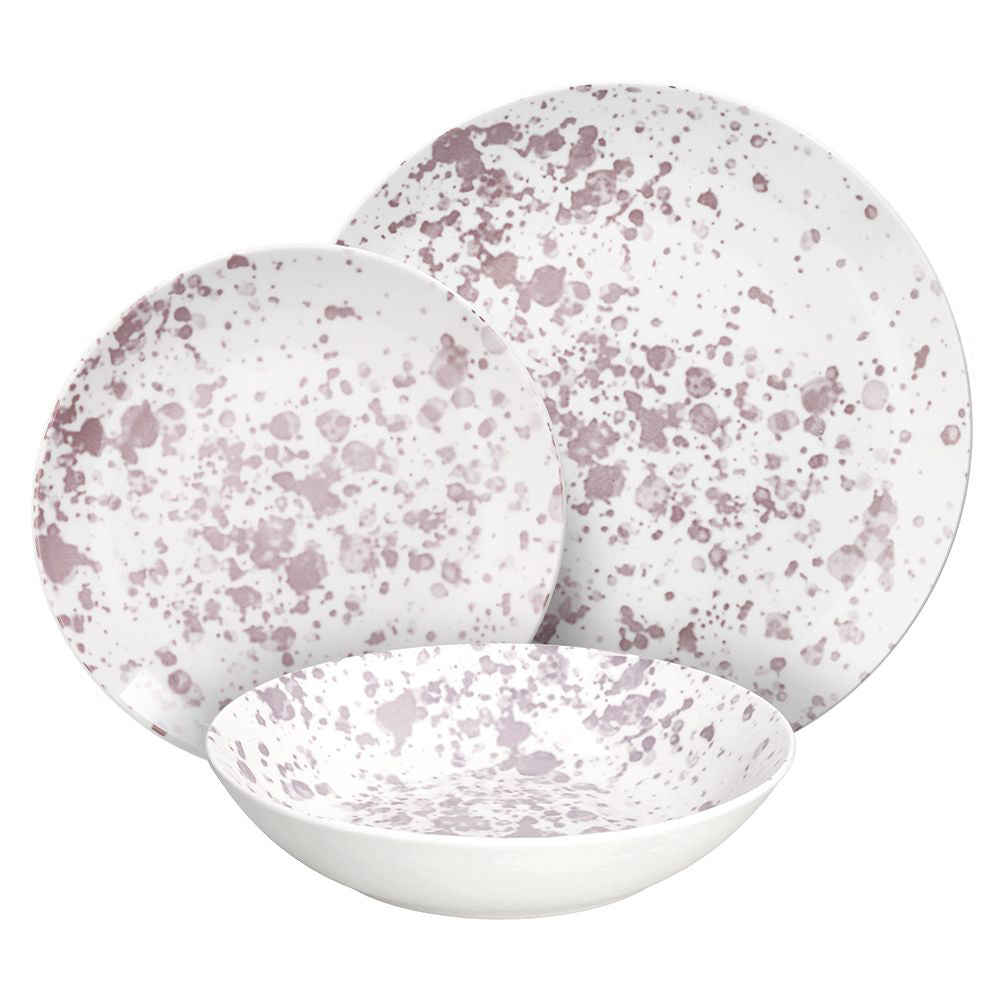 Set di tre piatti in ceramica bianca con macchie rosa, composto da un piatto fondo, uno piano e uno per dolce, su sfondo bianco.