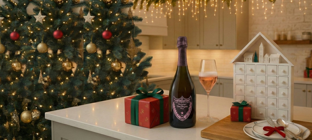 Weihnachtsbaum geschmückt mit Lichtern, roten und goldenen Kugeln, Flasche Dom Pérignon Rosé Champagner, Glas mit Roséwein und zwei kleine Geschenkpakete