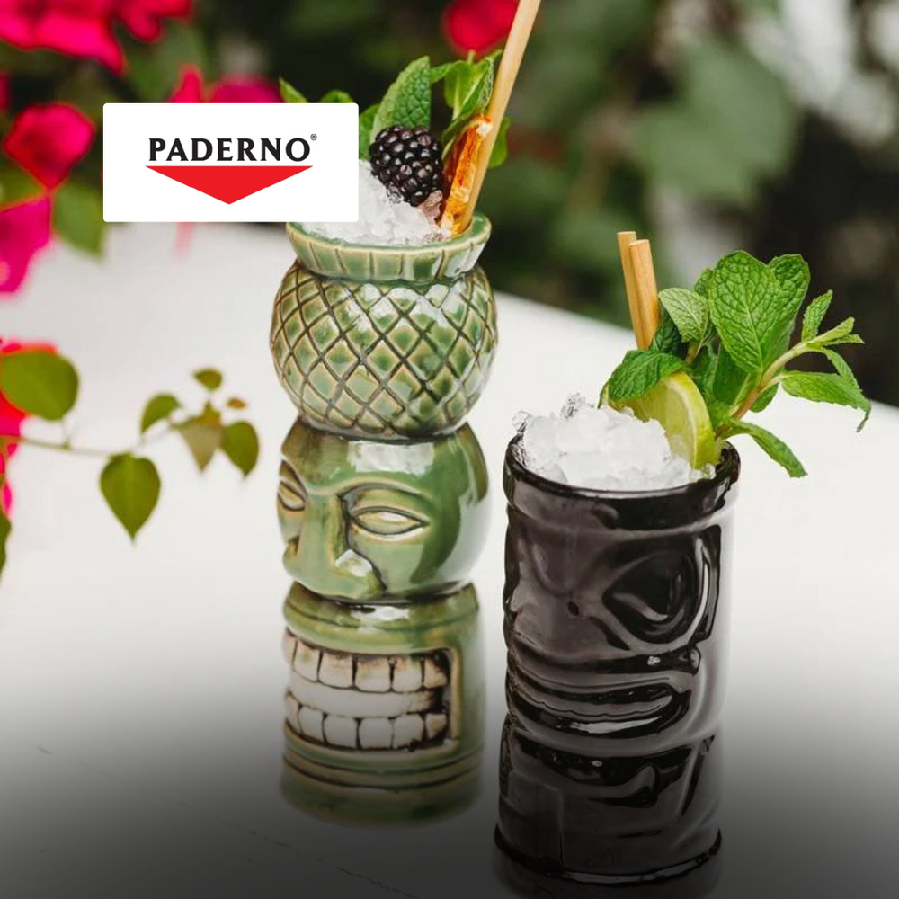 deux verres tiki en céramique, un vert avec ananas, un noir, tous deux avec glace, citron vert et menthe