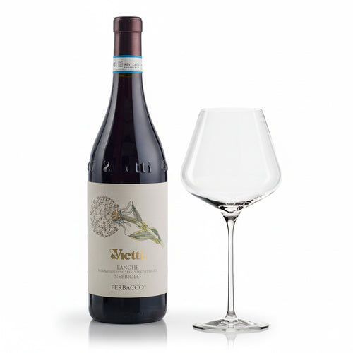 Bouteille de vin rouge Vietti Langhe Nebbiolo Perbacco avec étiquette beige et dessin de fleur et calice en verre transparent à côté sur fond blanc.