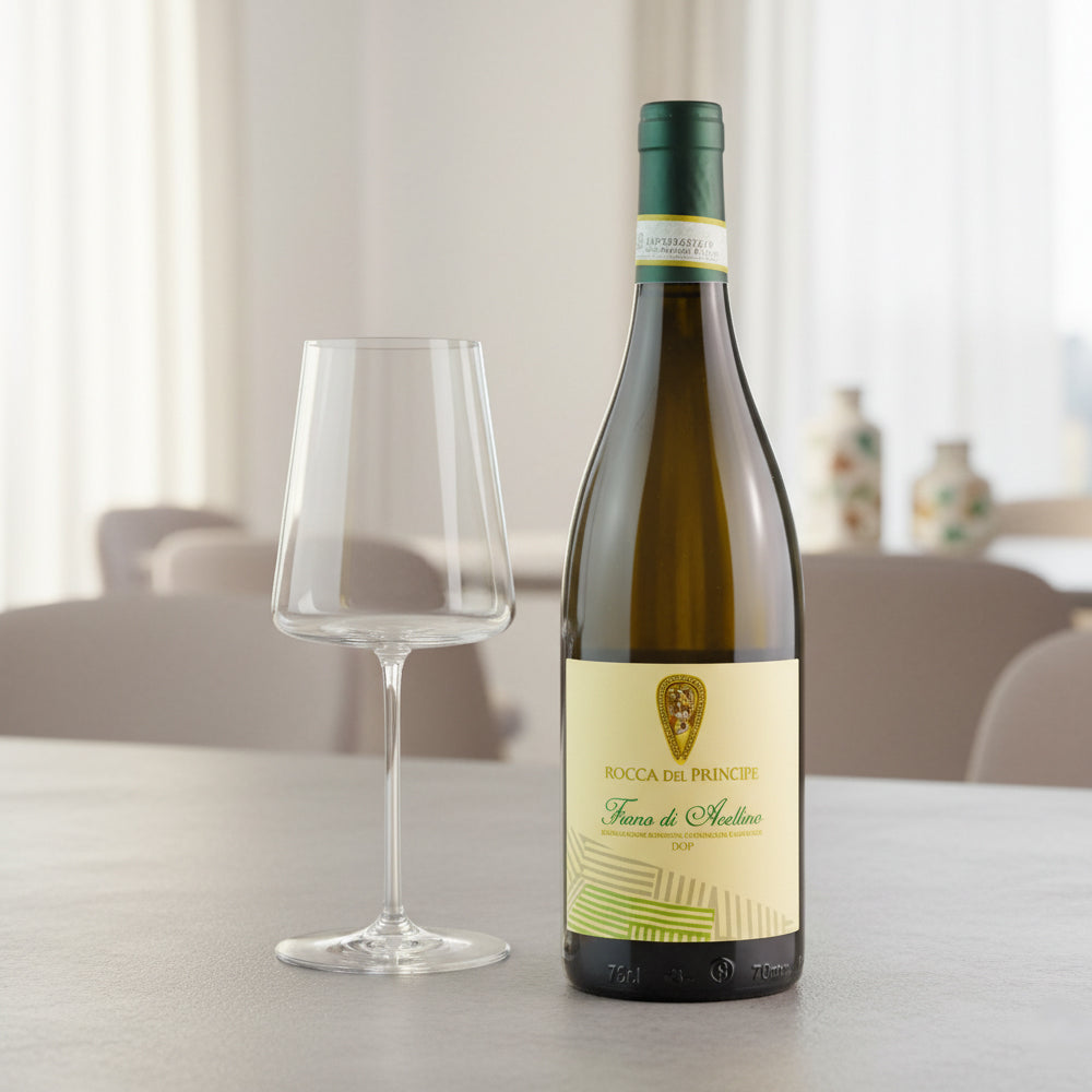 Rocca del Principe Fiano di Avellino DOP witte wijnfles met beige en groen etiket naast een transparant wijnglas op tafel