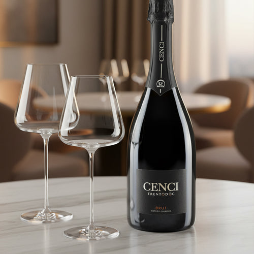 Bouteille de spumante Cenci Trentodoc Brut noire avec étiquette et deux calices en verre transparent sur table blanche, fond intérieur flou.