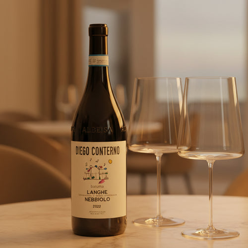 Bouteille de vin rouge Diego Conterno Langhe Nebbiolo 2022 avec deux calices transparents sur table ronde blanche en intérieur flou.