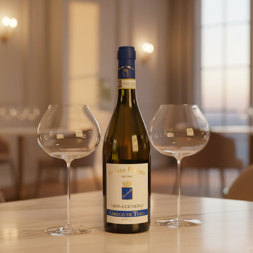 Bouteille de vin blanc Benito Ferrara Greco di Tufo avec bouchon bleu et deux verres en verre transparent sur table dans un intérieur élégant.