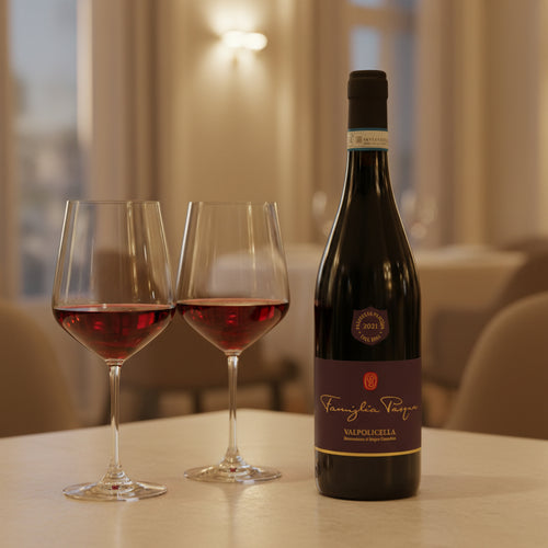Bouteille de vin rouge Valpolicella Famiglia Pasqua 2021 à côté de deux calices avec vin rouge sur table claire en intérieur élégant.