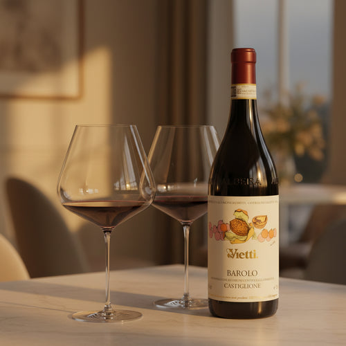 Bouteille de vin rouge Vietti Barolo Castiglione avec étiquette beige et dessins colorés, accompagnée de deux verres à vin sur table claire.