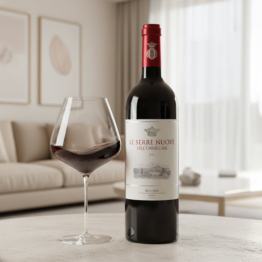 bottiglia di vino rosso Le Serre Nuove dell'Ornellaia 2021 con bicchiere parzialmente pieno su tavolo in ambiente soggiorno luminoso colore beige