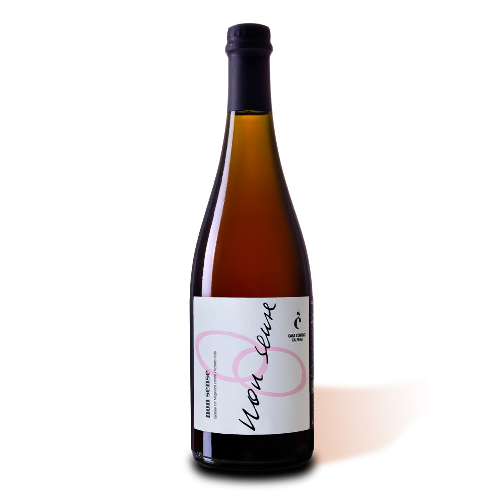 Bouteille en verre ambré avec étiquette blanche portant inscriptions noires et roses "non sense" et logo Casa Comerci Calabria sur fond