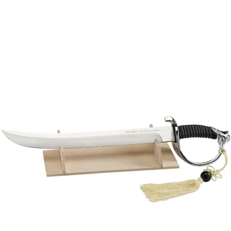 Sable con hoja de acero brillante y mango negro con empuñadura envuelta sobre base de madera clara con borla