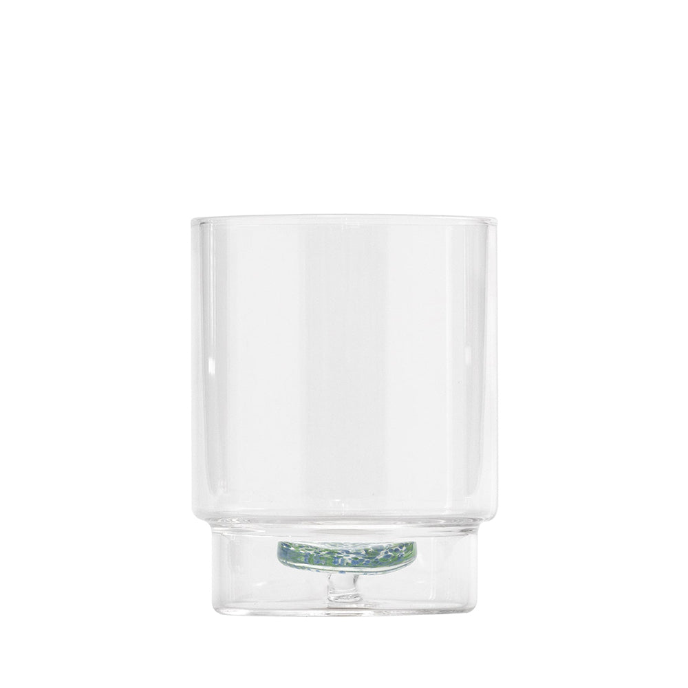 Bicchiere trasparente in vetro con base decorata verde e bianca, sfondo bianco, forma cilindrica.